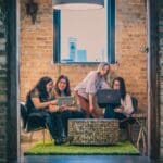 four women working, looking at computers