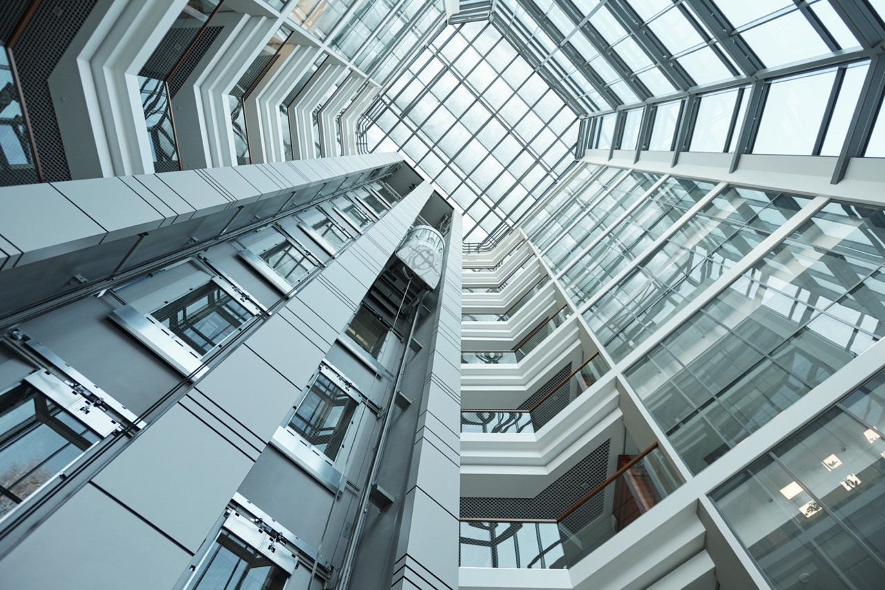 Part of interior of contemporary tall office building with moving elevator that can be used as background