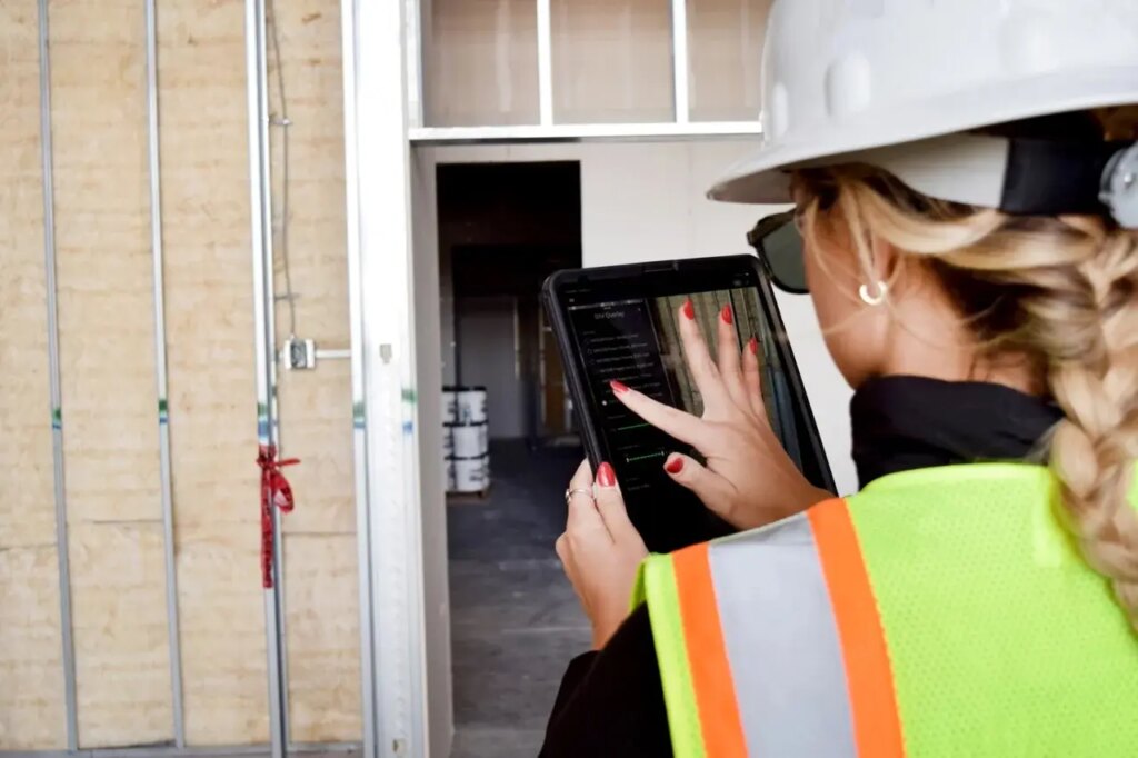 woman holding ipad in protective construction gear