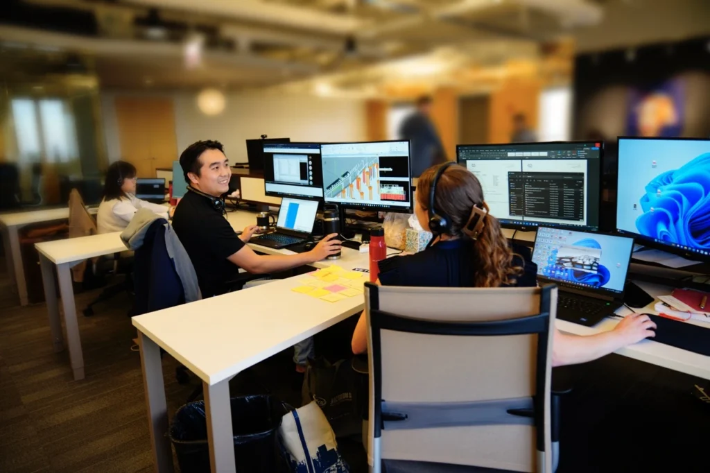 two viatechnik team members on computers chatting with each other